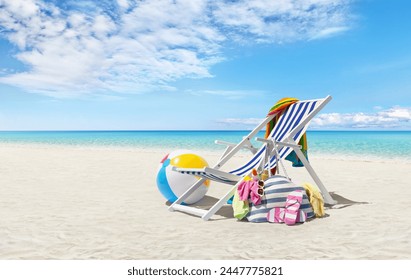 Beach deck chair for sunbathing on a sunny day by the seaside, beach ball and a bag full of accessories, concept of a summer beach holiday, online shopping, travel bookings, and resort accommodations - Powered by Shutterstock