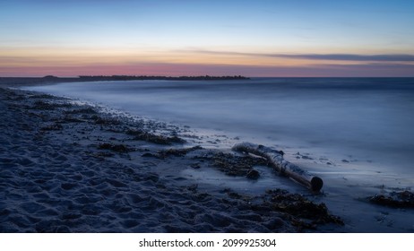 A Beach With Driftwood On A Calm Summer Night