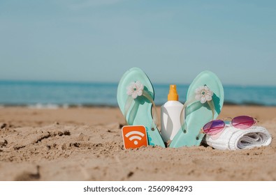Beach essentials: flip flops, sunscreen, towel, WiFi sign and sunglasses on sandy shore