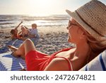 Beach, family and woman relax on chair in sunlight, blue sky adventure or bonding in summer holiday. Peace, mother and sunglasses rest by ocean, travel and freedom for tropical vacation in Greece