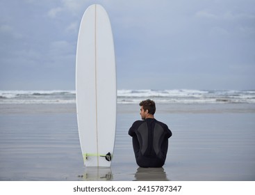 Beach, fitness and man thinking with a surfboard for wellness, sports and training while sitting in nature. Water, exercise and back of male surfer at the ocean with peace, calm and sea hobby in Bali - Powered by Shutterstock