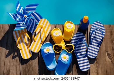Beach flip-flops and sunglasses on wooden background. Things for vacation against blue water of swimming pool. Summer holiday and travel concept