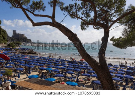 beach full of umbrellas, the marina and the castle of Lerici (Italy) in the background