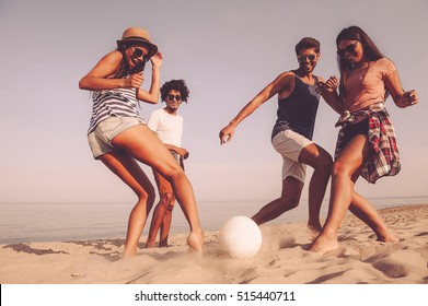 Beach fun with friends. Group of cheerful young people playing with soccer ball on the beach - Powered by Shutterstock