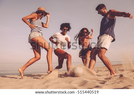 Beach fun. Group of cheerful young people playing with soccer ball on the beach