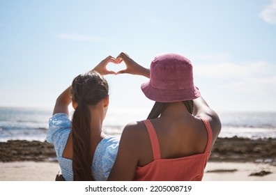 Beach, Heart Sign And Women Friends With Love For Summer And Ocean On Blue Sky And Sunshine. Behind Of Lesbian Couple Or Gen Z People With Care Hands, Icon Or Emoji For Outdoor Vitamin D Or Earth Day