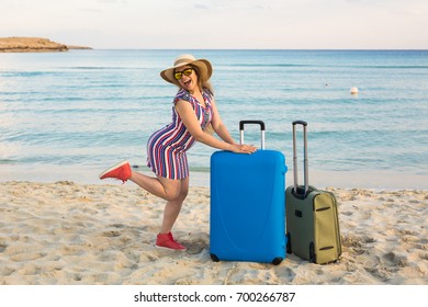 Beach, Holiday, Vacation and Happiness Concept - young smiling woman near the sea with her luggage