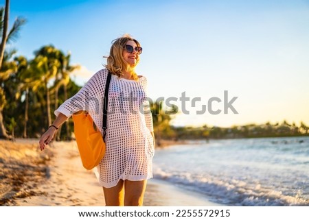 Beach holiday - woman walking on sunny, tropical beach in the morning 
