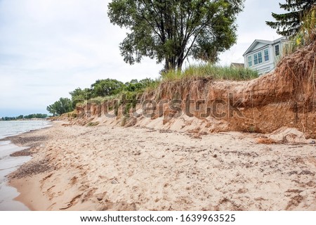 Beach houses on Lake Michigan, lake erosion dangerously close to the houses, focus on bluff in center of image