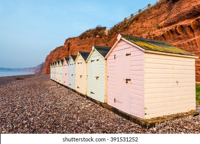 Beach Hut Row In Pastel Colors, Red Rock Cliff Background, South Devon, UK