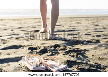 Beach Jandals/ a woman leaves her Flip-flops on the dry sand to go for a swim
