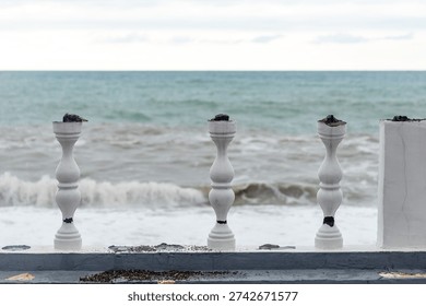 The beach is lined with three white pillars, standing tall and proud against the backdrop of the ocean. The pillars are positioned close to the water, creating a sense of serenity and tranquility