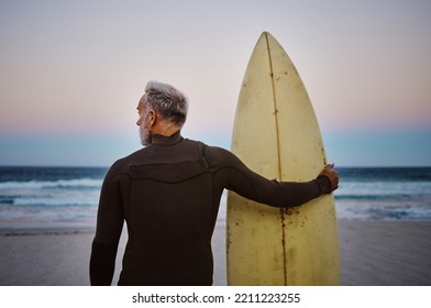 Beach, man and surfboard with back view for morning cardio fitness and tranquil swim in nature. Senior surfer waiting for low tide at ocean for calm surf waves with peaceful sky at dawn. - Powered by Shutterstock