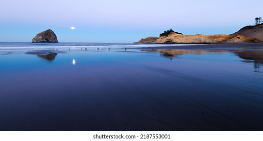 Beach Panorama At Pacific City Oreagon With Haystack Rock And Cape Kiwanda Headland In Dawn Light As Full Moon Sets