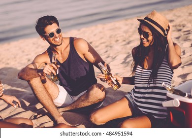 Beach Party With Friends. Cheerful Young People Spending Nice Time Together While Sitting On The Beach And Drinking Beer