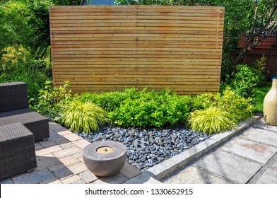 Beach pebbles, square cut flagstone and brick landscape pavers and simple plantings provide ample texture and contrast in this small contemporary backyard Asian inspired urban garden.
