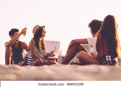 Beach Picnic With Friends. Cheerful Young People Spending Nice Time Together While Sitting On The Beach And Drinking Beer