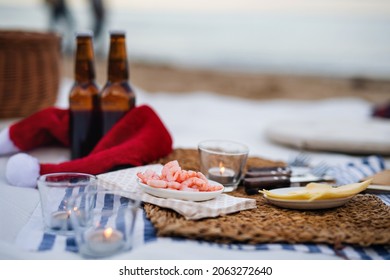 Beach Picnic With Schripms, Beer, Candles And Santa Hat. Exotic New Year And Christmas