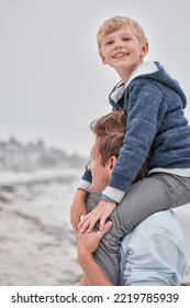 Beach, Portrait Of Dad And Child On Shoulders With Smile On Family Holiday Or Cloudy Ocean Walk In Australia. Travel, Fun And Happy Father And Son Playing And Walking At Sea On Vacation With Gray Sky