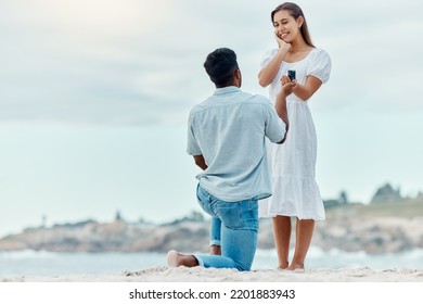 Beach proposal, engagement and surprise woman for love, care and relationship commitment together. Young, engaged and happy marry me couple, summer seaside date and special romance marriage outdoors