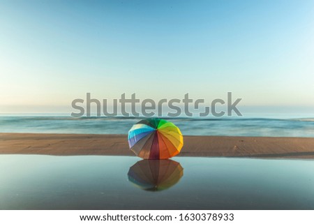 Similar – Colorful striped, closed parasol in close-up on the beach at sunset