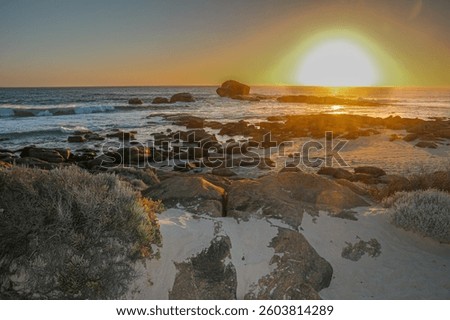 Beach with rocks the ocean and the setting sun with a halo around the sun