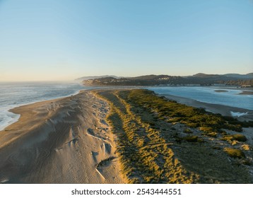 A beach with a rocky shoreline and a body of water in the background. The sky is clear and the sun is shining brightly - Powered by Shutterstock