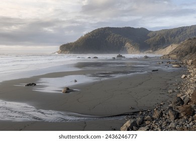 A beach with a rocky shoreline and a cloudy sky. The beach is empty and the water is calm - Powered by Shutterstock