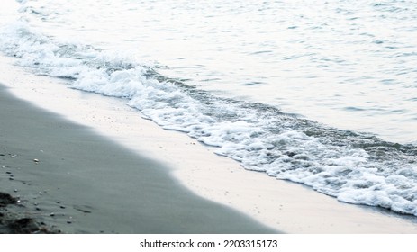 Beach sand sea water summer background. White foam wave sandy seashore top view.