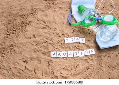 Beach Sand With Toys For The Baby, Water, The Word Holi Stay In Colored Letters. Staycation Content