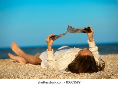 Beach Scene. Young Woman Reading Magazine