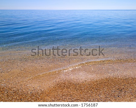 Beach and sea background.  high resolution mediterranean beach and sea scene in summer, with waves lapping in foreground.  Focus is one third up from bottom of frame.