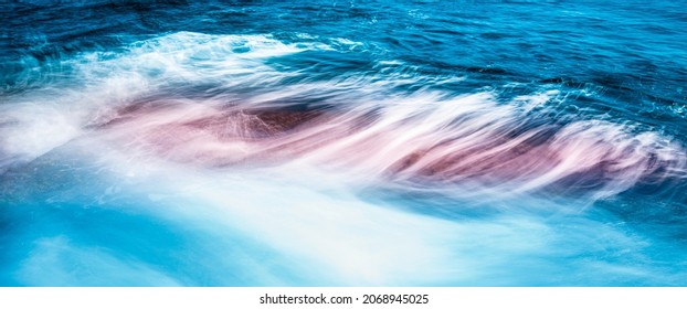 Beach seascape with soft waves over the rocky beach with motion blur effect of long exposure photography.