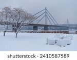 Beach seats under the snow with cable-bridge on the background, Novi Sad