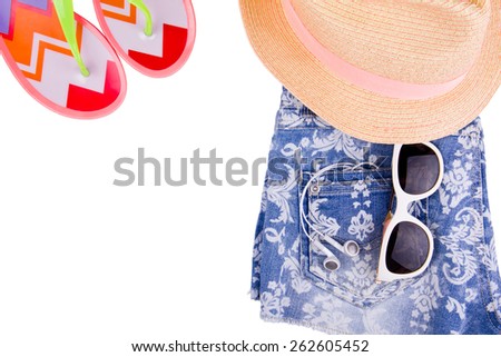 Beach set - Denim blue jeans shorts with white pattern, hat with pink stripe, sunglasses and color beach slippers are isolated on white background. Headphones is in back pocket. 