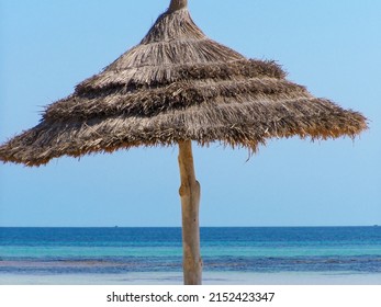 A Beach Straw Umbrella Against The Horizon Of The Sea