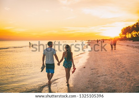 Beach summer beach people lifestyle happy couple enjoying sunset walk on Shelling beach famous tourist destination on the southwest coast of Florida -Gulf of Mexico. Sanibel Island, Florida.