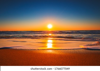 Beach sunrise or sunset with clear blue sky and rising sun