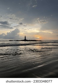 Beach in the sunset and lighthouse.