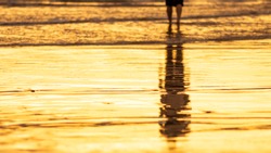 Beach Sunset With Silhouette Of A Woman Reflecting On Water Surface