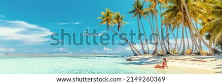 Beach suntan bikini woman sunbathing lying in ocean drinking tropical drink. Travel vacation paradise banner panorama background copy space on blue sky