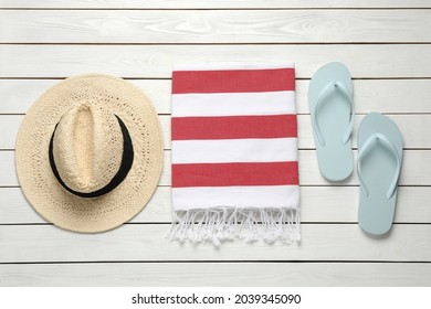 Beach towel, flip flops and straw hat on white wooden background, flat lay - Powered by Shutterstock