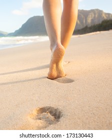Beach travel - Woman walking on sand beach in Hawaii leaving footprints in the sand.