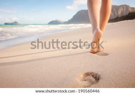 Beach travel - young girl walking on sandy beach leaving footprints in the sand, Hawaii, USA.