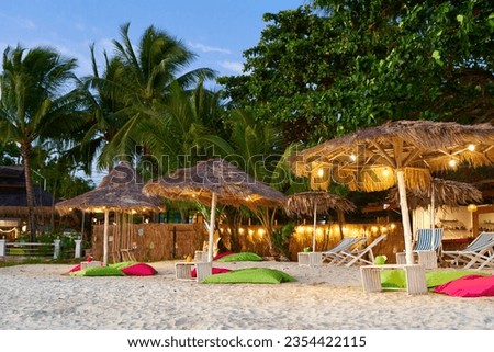 Beach umbrella made of dried palm fronds on a tropical island beach. A luxurious vacation concept.