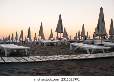 Beach umbrellas by the sea at sunrise - Shutterstock ID 2311025991