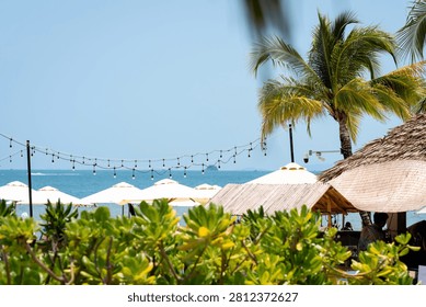 Beach umbrellas and palm trees framing bright turquoise Phu Quoc sea with tropical greenery
