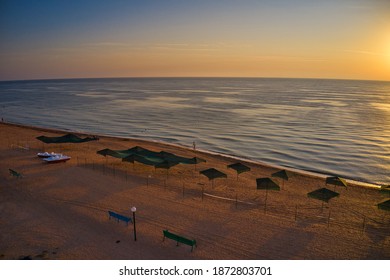 Beach Umbrellas At Sunrise. Sea Current Swims Against The Waves On The Beautiful Sea