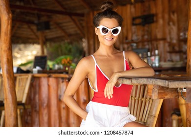 Beach Vacation Concept. Young And Sexy Woman Sitting In Authentic Beach Bar With A Coconut Drink 