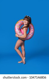 Beach Vacation concept.Isolated on Blue background. Pretty child model cute smile.Fashion beauty little girl swimsuit,inflatable ring.Advertising rest beach,summer vacation,travel.